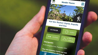 Hand mit Smartphone auf dem die Nationalpark-App gestartet ist.
